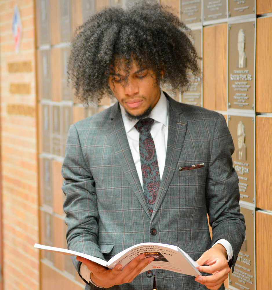 COBA student reading in front of plaques.