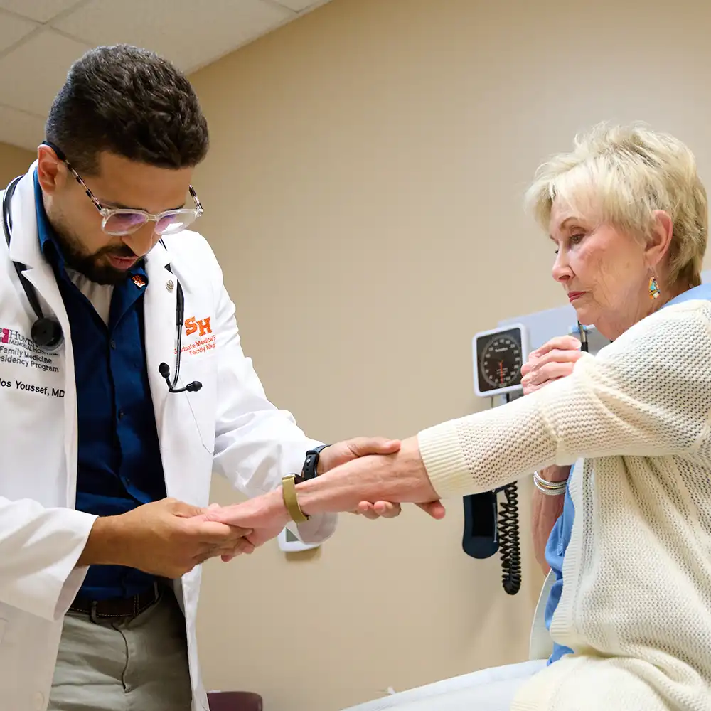Resident standing and smiling with backlighting from a medical light behind her