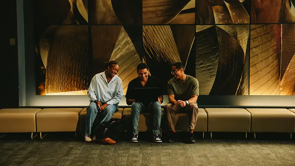 Three students sitting in lobby.