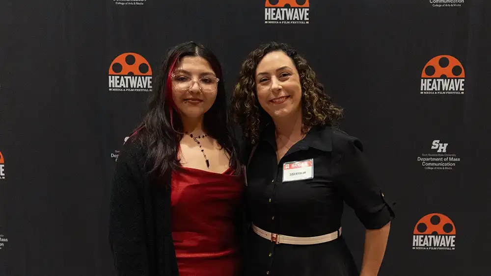 Professor speaking to the camera in a classroom style class, with her hands opened.