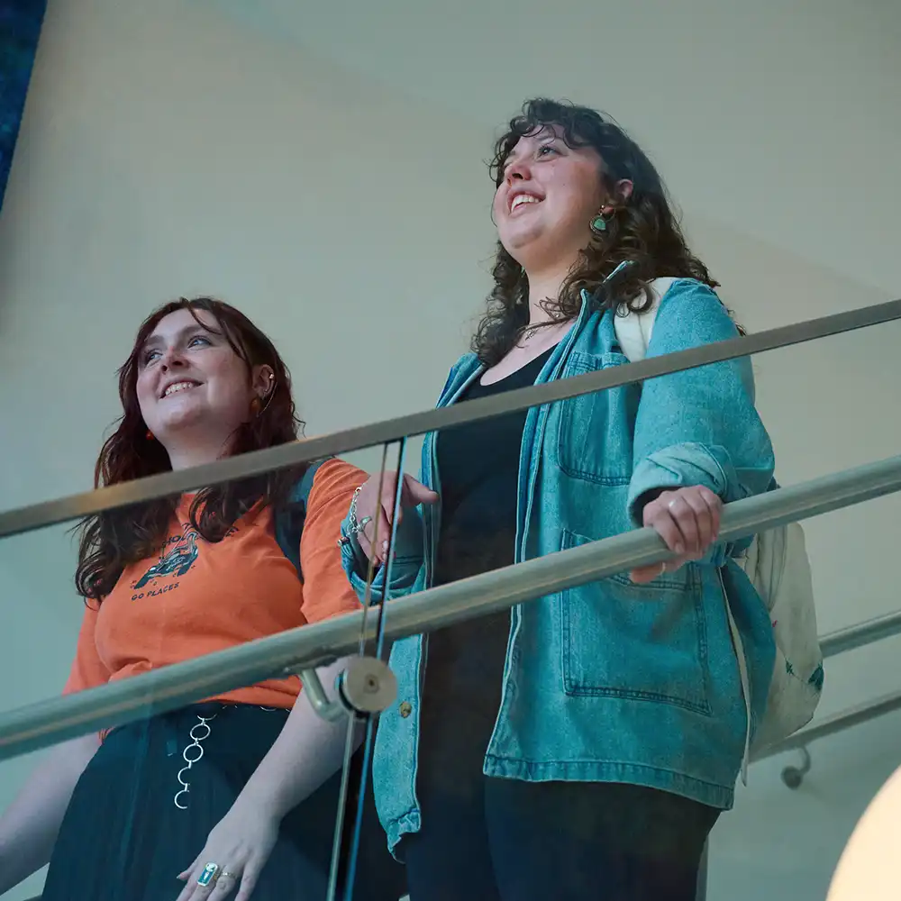 Two students walking down the stairs in the CHSS building.