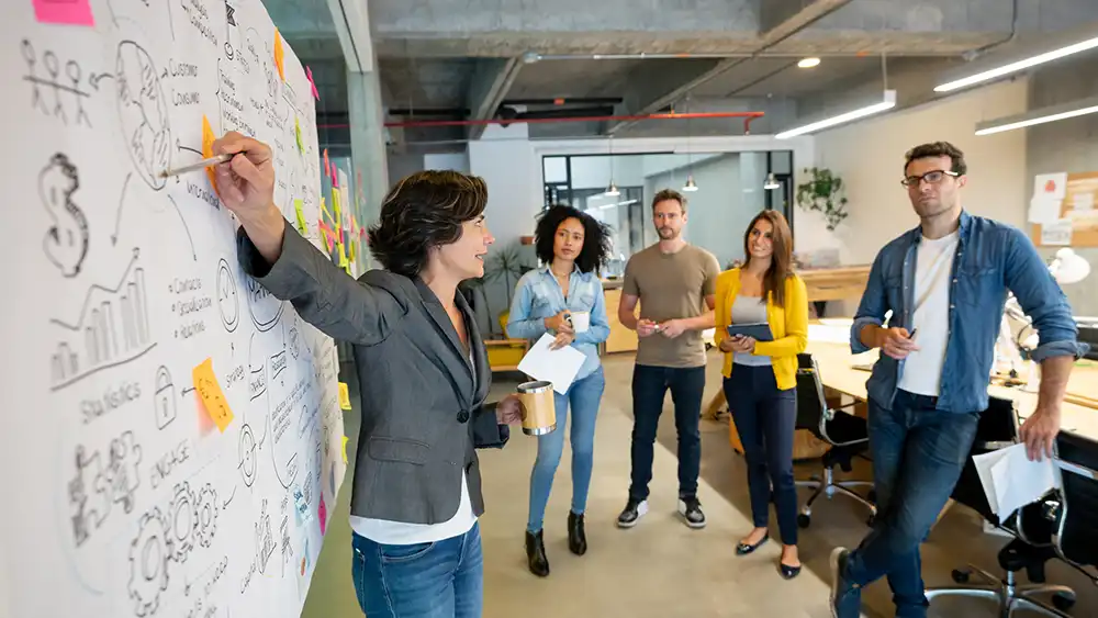 Professor working at white board with group of students. 