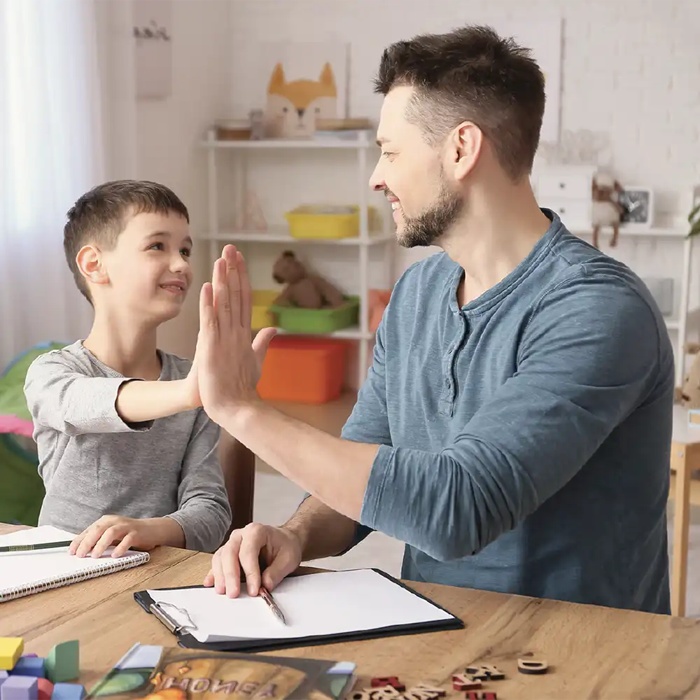 Two women looking at each other, smiling, sitting down, working on an assignment.