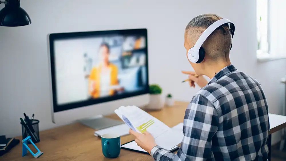Student watching professor instruction on a computer screen. 