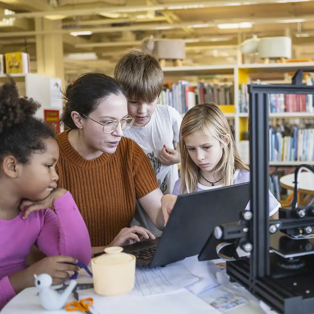 Teacher working with a young student on her computer. 