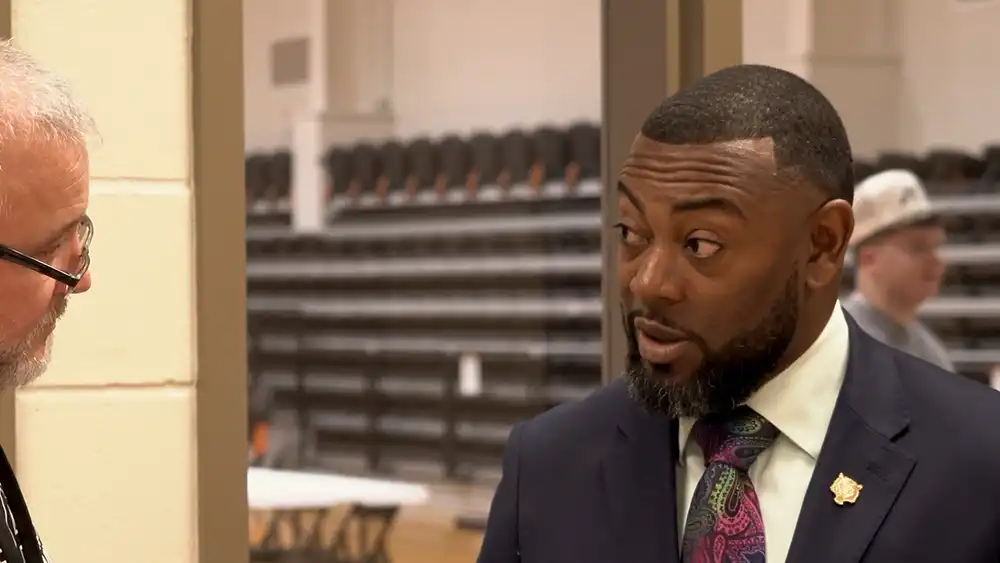 Man in a suit speaking to another man