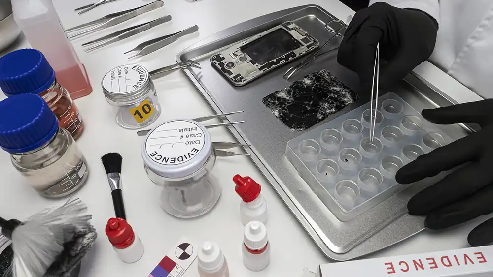 A person is working on a cell phone for evidence. 