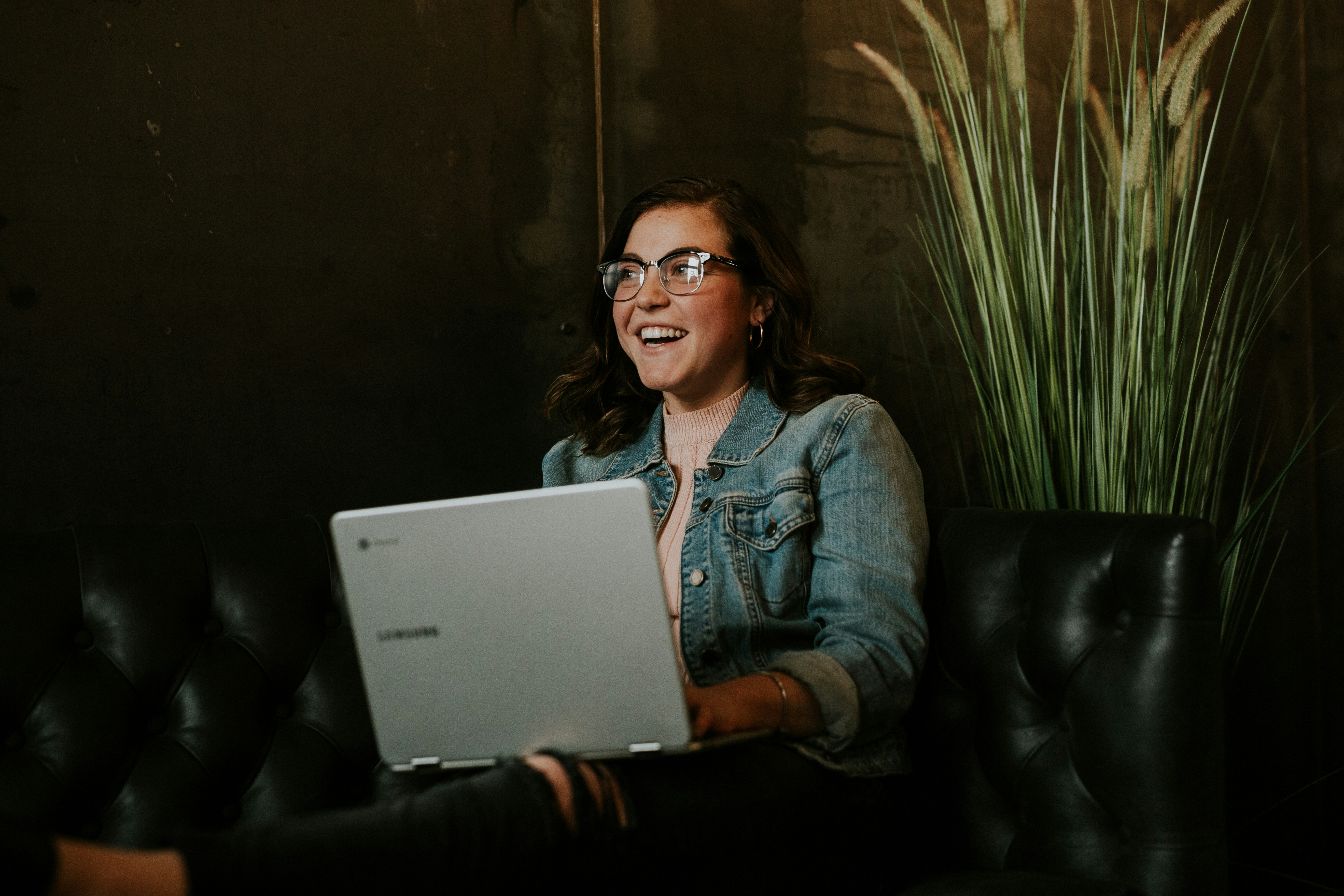 An online student smiles as they work on their laptop in a cafe.