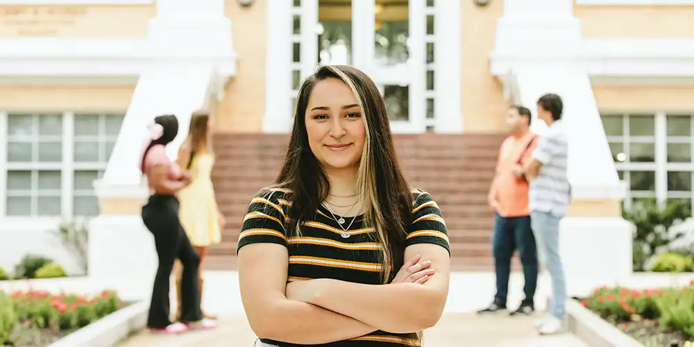 Female student standing outside with her arms crossed. 
