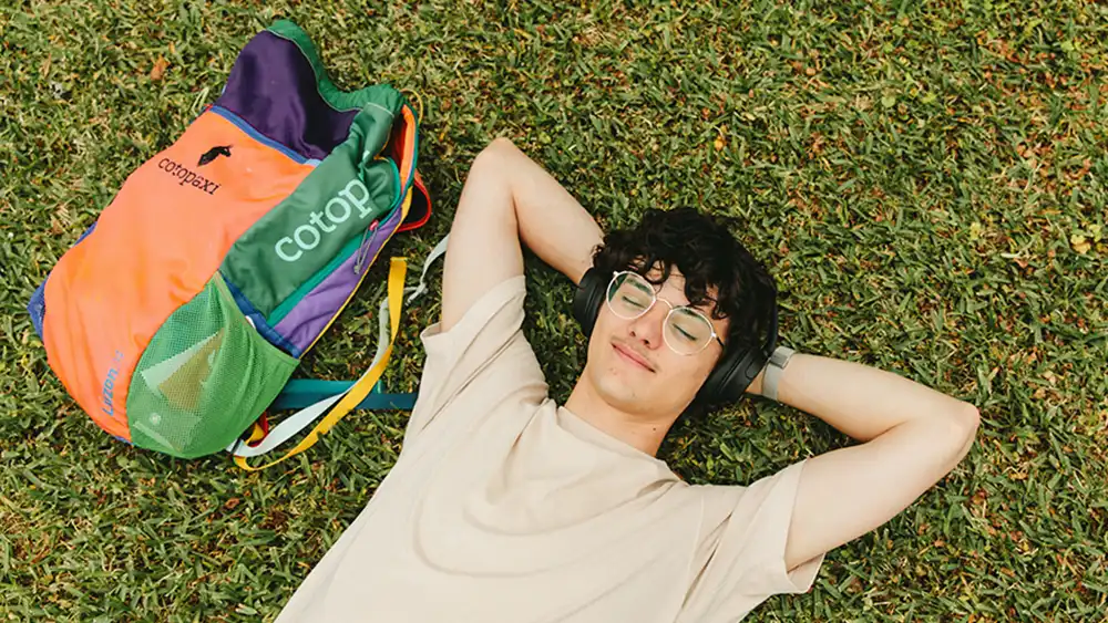 Male student laying on his back in the grass.