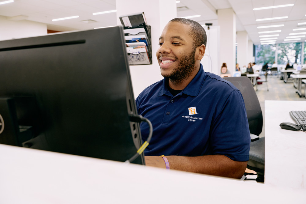 Student sitting at a desk behind a computer monitor