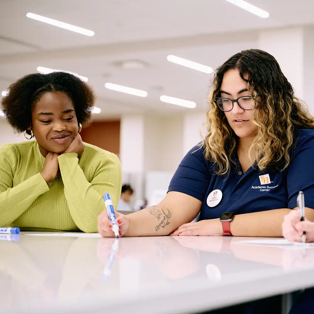 Tutor sitting in center, working with a student.