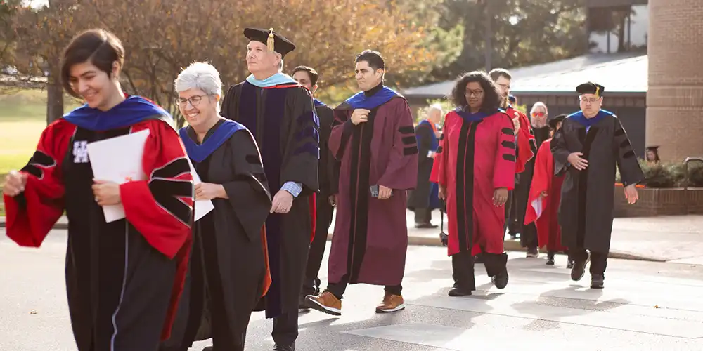 faculty in regalia climbing stairs to coliseum 