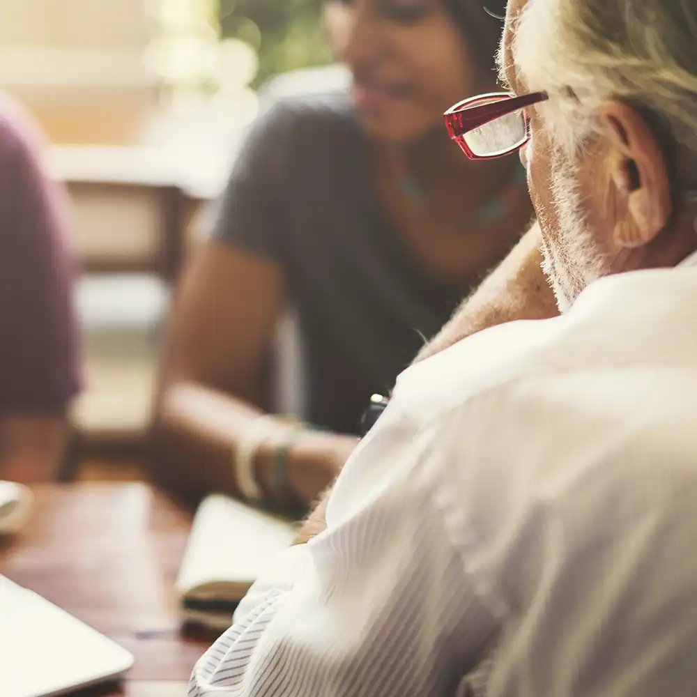 ​​Three people having a discussion around a laptop​ 