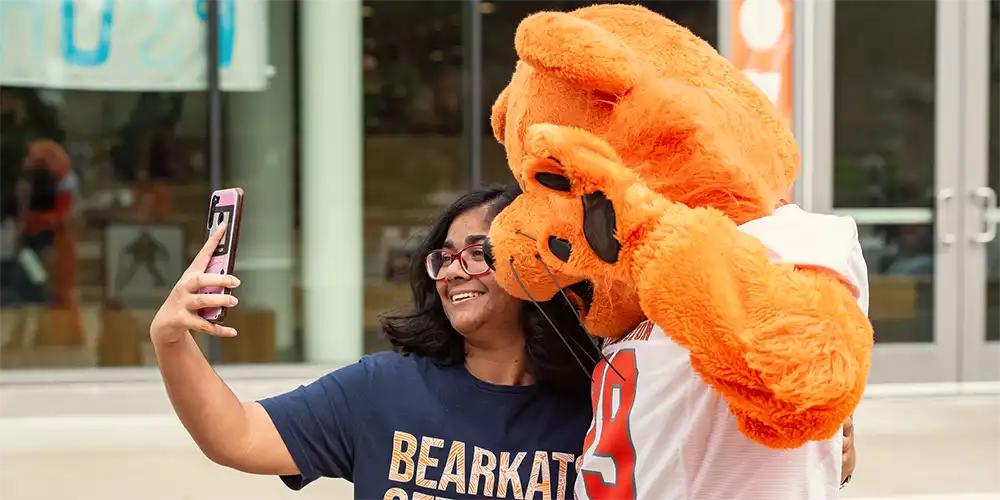 SHSU international student taking a selfie with Sammy the Bearkat.