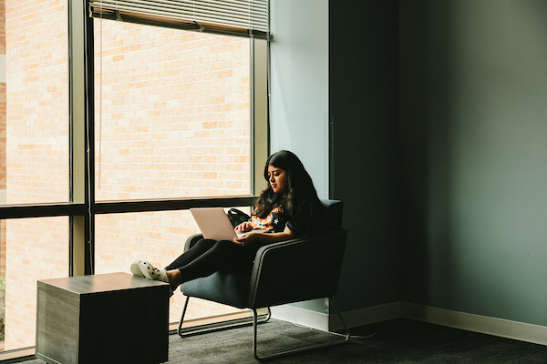 ​​Austin Hall at sunset illuminating behind statue of Sam Houston.​ 