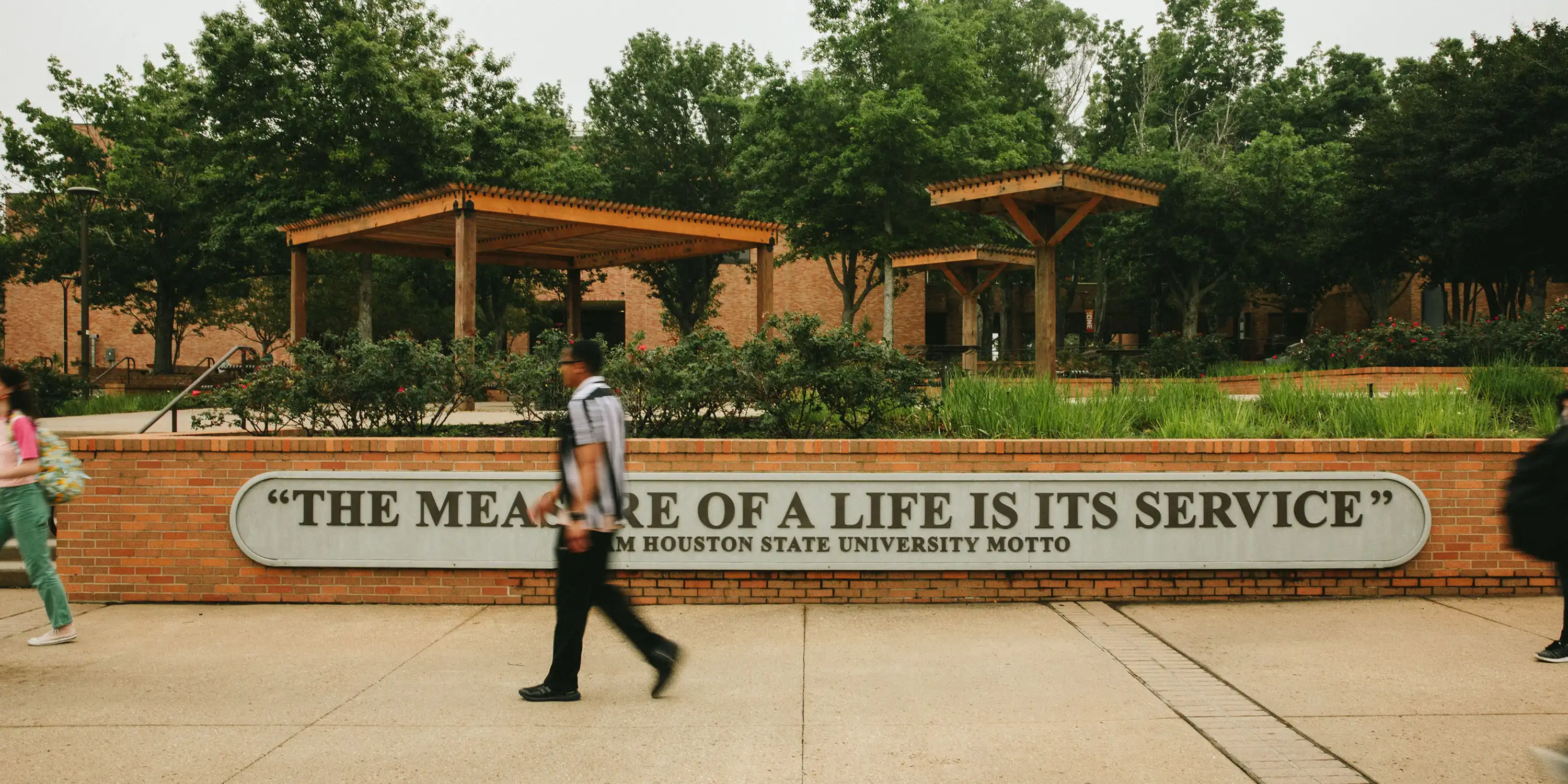 ​​Students walking by SHSU motto​