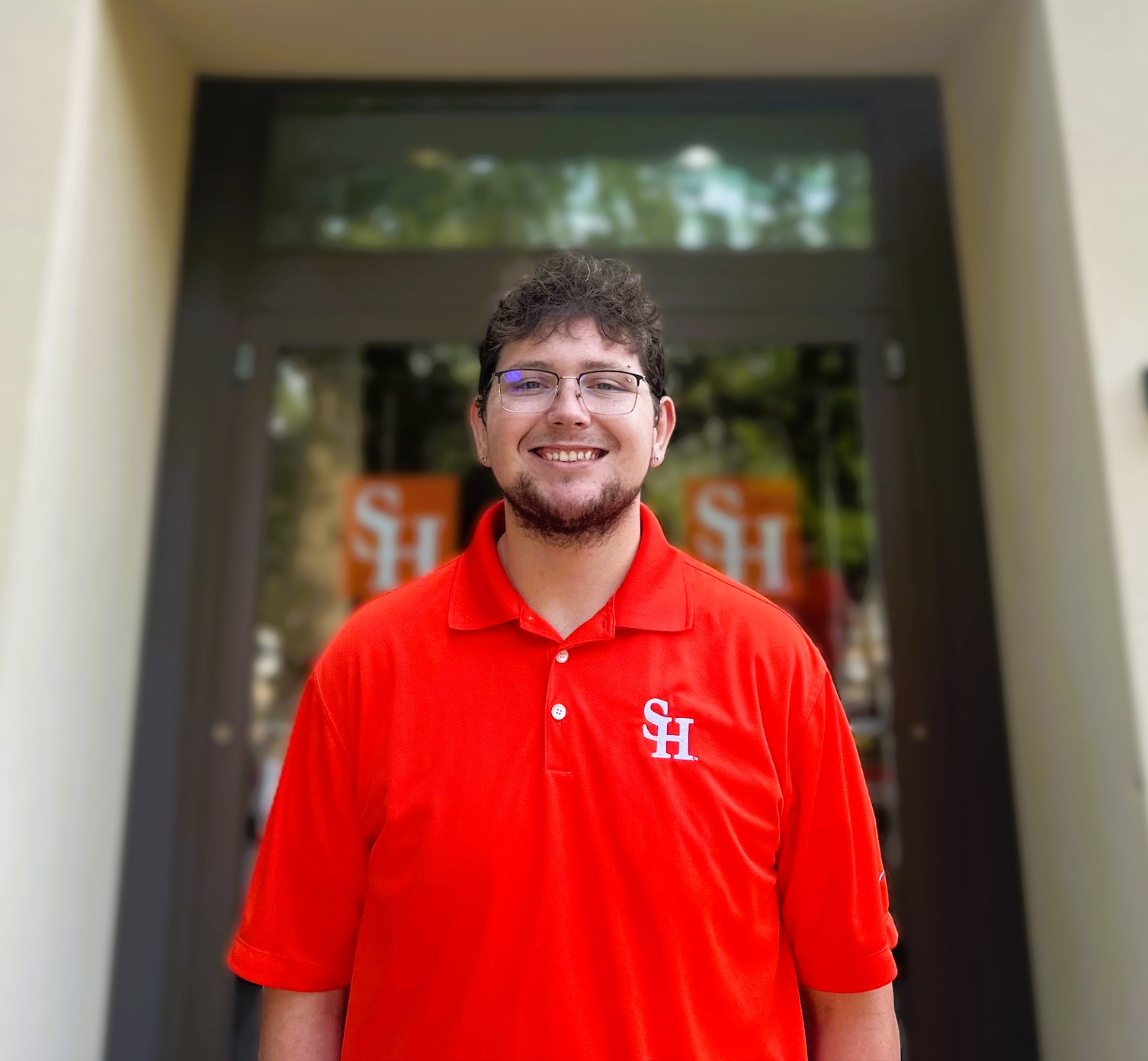 Photo of Daniel Cole Peacock in front of the Sam Houston State University Visitor Center. 